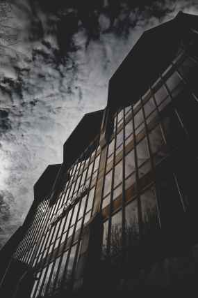 brown concrete building with glass window under gray sky